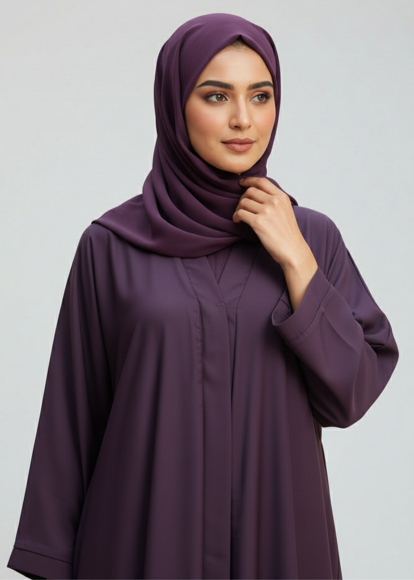 Woman wearing a dark purple abaya and hijab on a light gray background