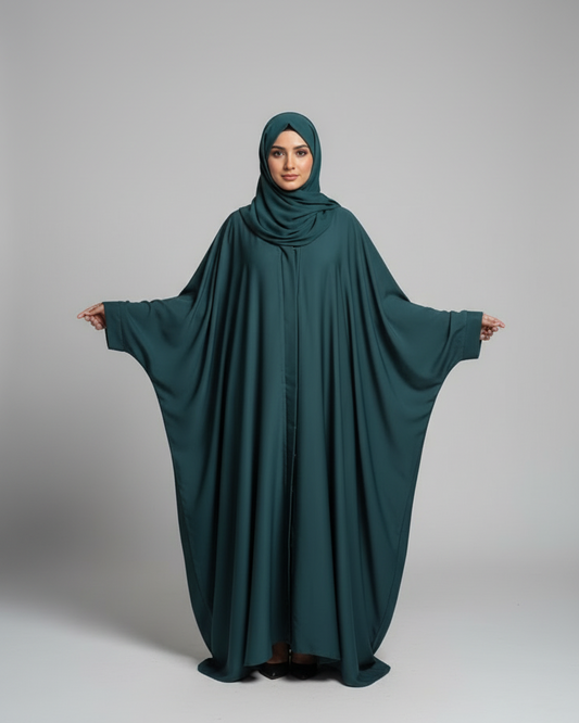Woman wearing a teal abaya on a gray background