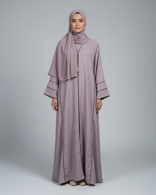 Woman wearing a mauve abaya and hijab on a gray background