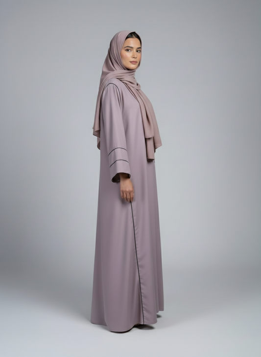 Woman wearing a long, light purple dress with a matching hijab on a gray background
