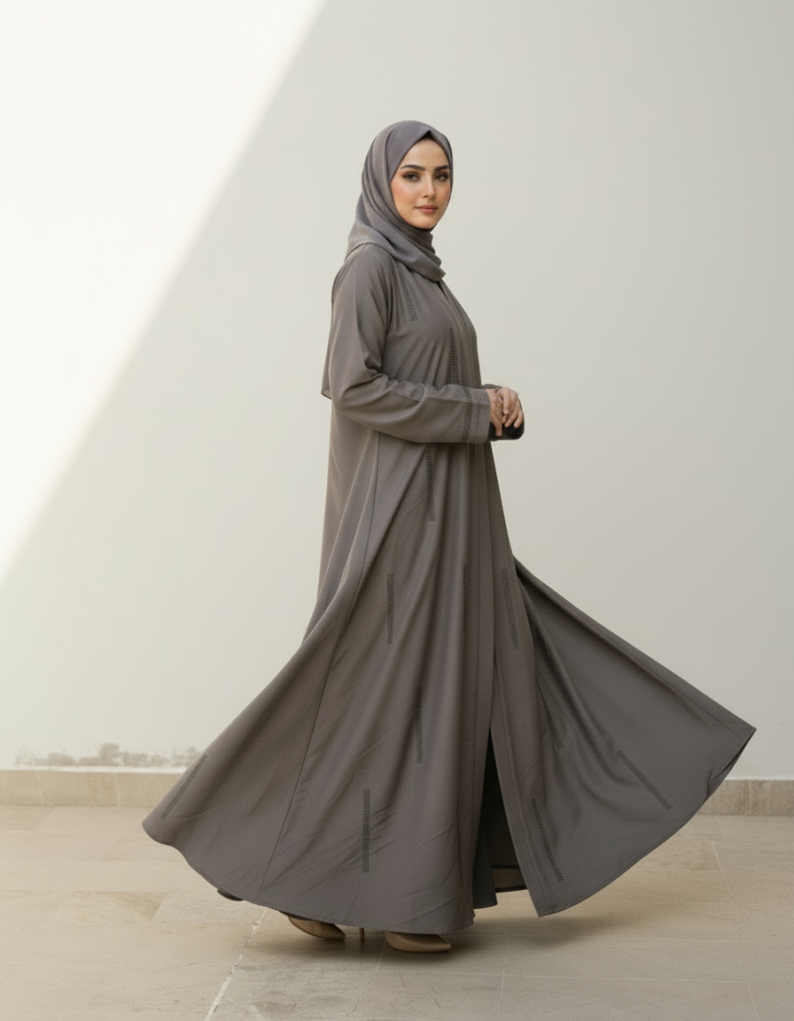 Woman wearing a long gray dress and hijab against a white background