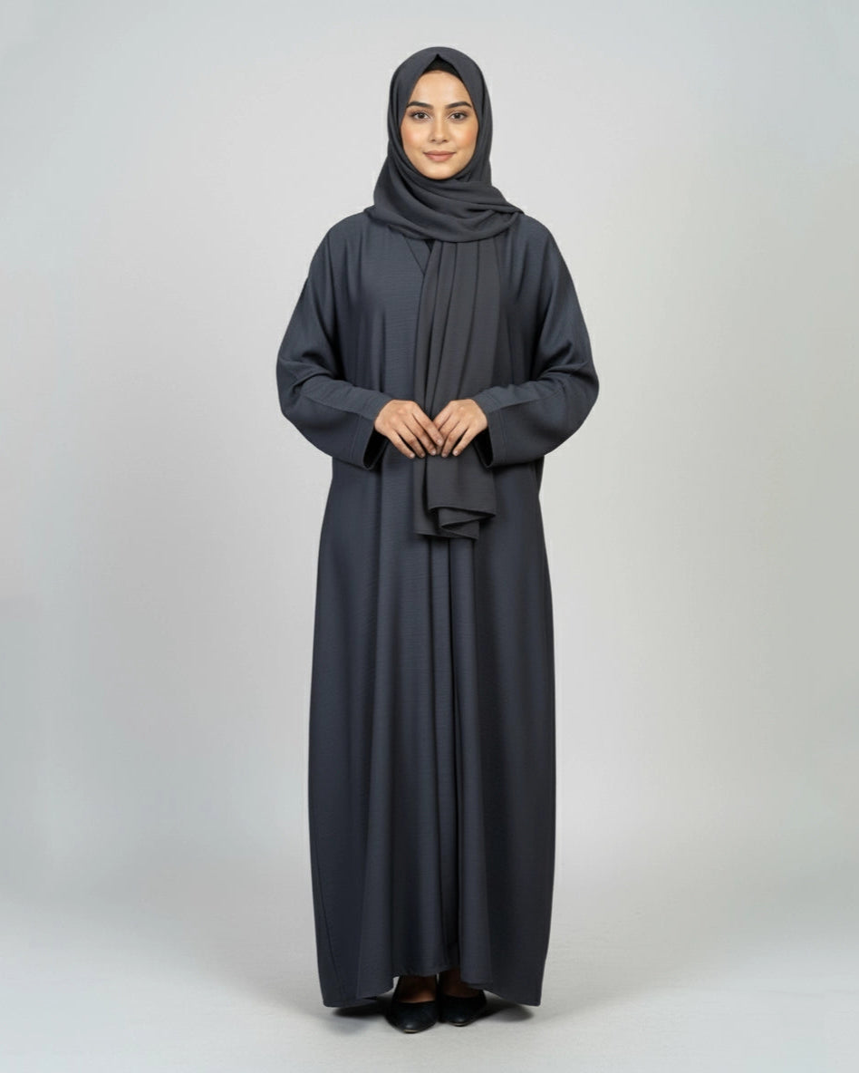 Woman wearing a dark gray abaya and hijab on a white background