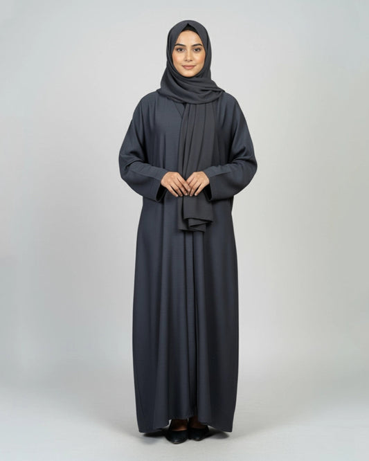 Woman wearing a dark gray abaya and hijab on a white background