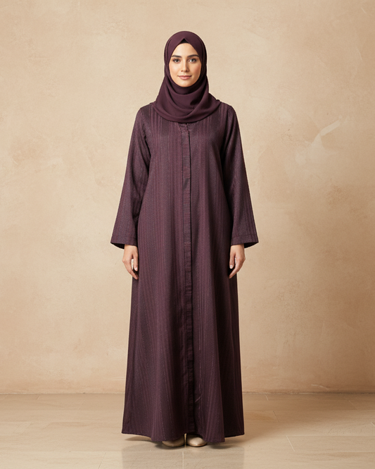 Woman wearing a long dark purple dress and hijab against a beige background