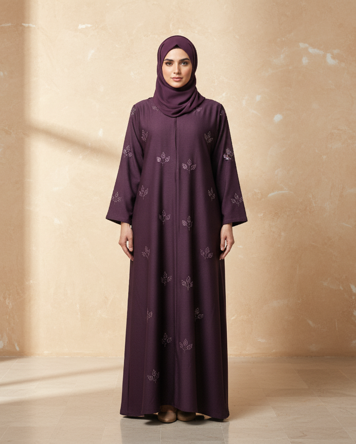 Woman wearing a purple abaya with floral patterns against a beige wall.