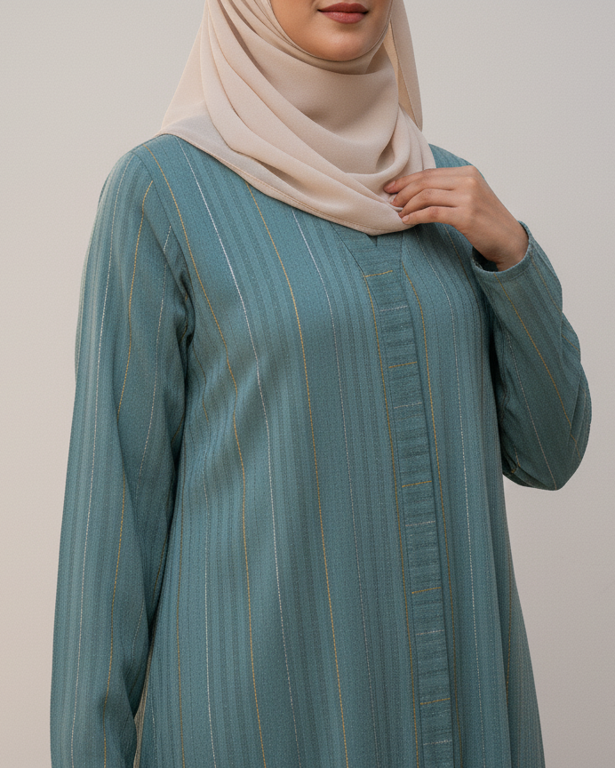 Woman wearing a teal dress with long sleeves and a beige hijab on a plain background