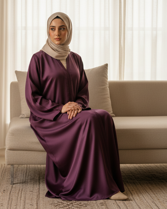 Woman in a purple dress sitting on a beige couch in a well-lit room.