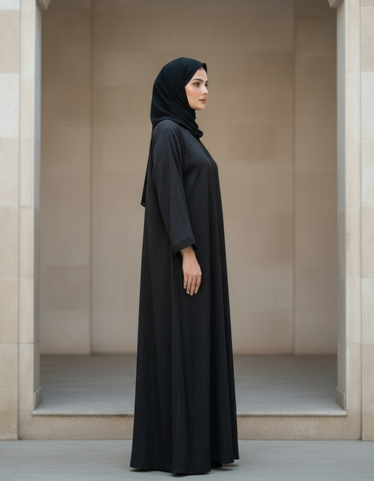 Woman wearing a black abaya standing in an architectural setting