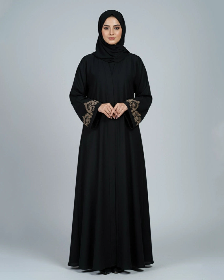 Woman wearing a black abaya with floral embroidery on the sleeves against a gray background