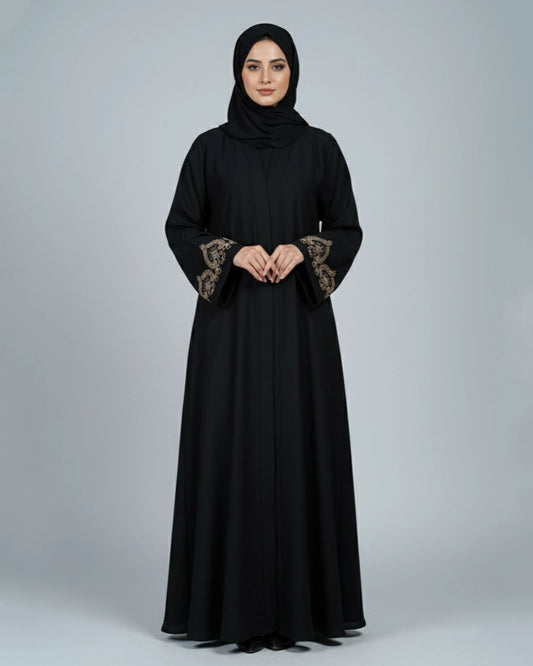 Woman wearing a black abaya with floral embroidery on the sleeves against a gray background