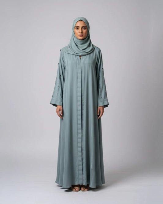 Woman wearing a long, light blue abaya with a matching hijab on a white background